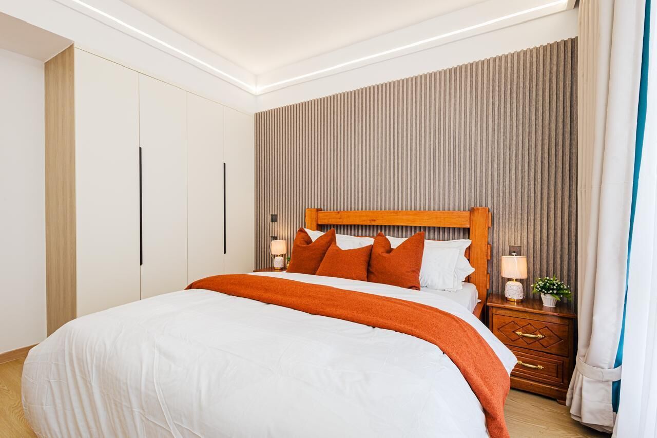 Una camera d'albergo con un letto grande, una testiera in legno, un comodino con una lampada e un armadio.