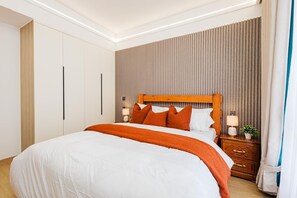Ein Hotelzimmer mit einem großen Bett, einem Holz-Kopfteil, einem Nachttisch mit Lampe und einem Kleiderschrank.