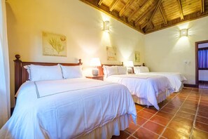 Habitación de hotel con dos camas, cabeceros de madera y suelo de baldosas.