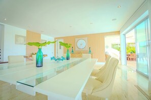 A modern dining area with a glass table, chairs, and decorative vases. - Villa Vega de Palma. Luxurious villa .Golf view (La Romana)