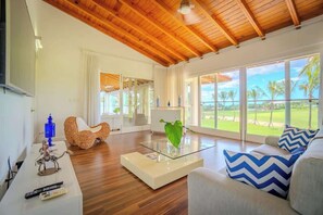 A spacious living room with a wooden ceiling, large windows with a view of a golf course, and modern furniture. - Villa Vega de Palma. Luxurious villa .Golf view (La Romana)