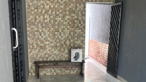 A corridor with tiled flooring, a bench, and a wall with a textured pattern.