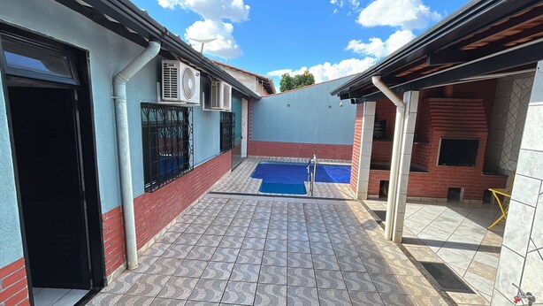 A courtyard with a swimming pool, a covered seating area, and a brick wall.