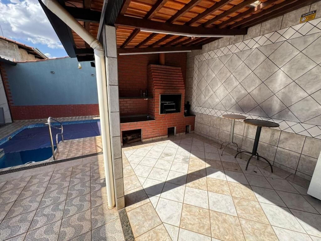 An outdoor patio with a brick fireplace, a pool, and a tiled floor.