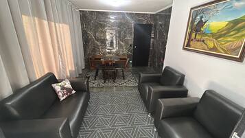 A living room with a sofa, a dining table, and a painting on the wall.