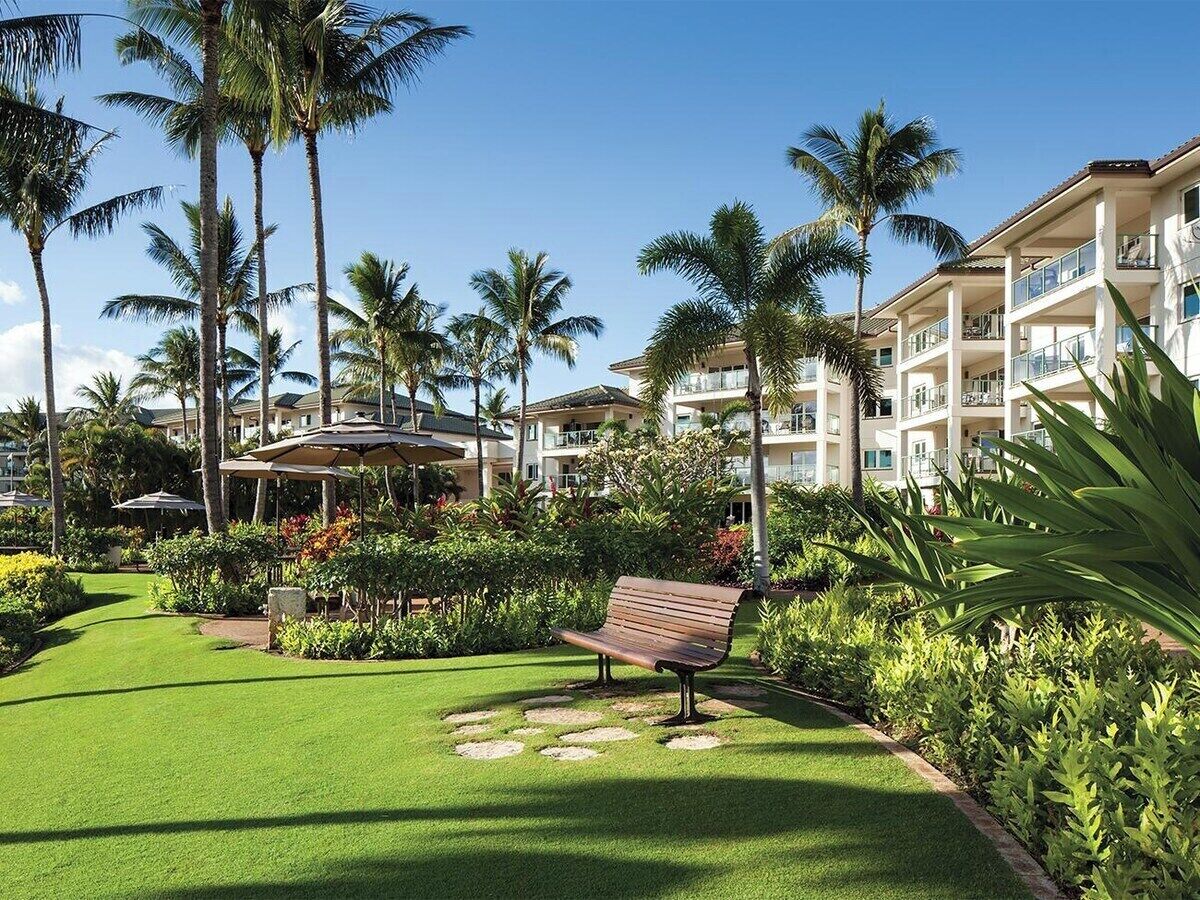 Ein Resort mit gepflegter Rasenfläche, Palmen und einem Gebäude mit mehreren Balkonen.