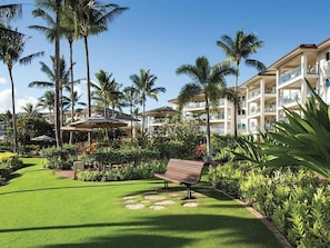 Ein Resort mit gepflegter Rasenfläche, Palmen und einem Gebäude mit mehreren Balkonen.