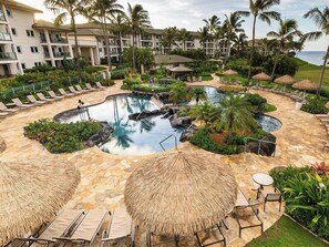 A resort with a circular pool surrounded by lounge chairs and umbrellas, palm trees, and a building in the background. - 3 Bedroom Villa at Marriott Kaua'i Lagoons (Lihue)