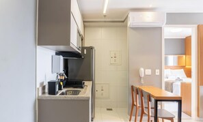 A compact kitchen with a built-in stove, a sink, and a small dining area with a table and chairs. - Apt in Condo w/ Pool in Jardim Goias Mbcb0801 (Goiânia)