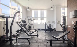 A gym with exercise equipment, large windows, and a TV on the wall. - Apt in Condo w/ Pool in Jardim Goias Mbcb0801 (Goiânia)