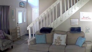 Ein Wohnzimmer mit einem beigen Sofa, einem gemusterten Sessel und einer Treppe.