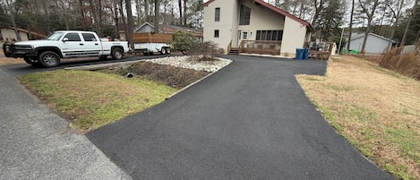 A residential driveway leading to a house with a wooden deck and a garage.