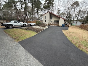 A residential driveway leading to a house with a wooden deck and a garage. - Cozy 3-bedroom house in charming Ocean Pines with AC (Ocean Pines)