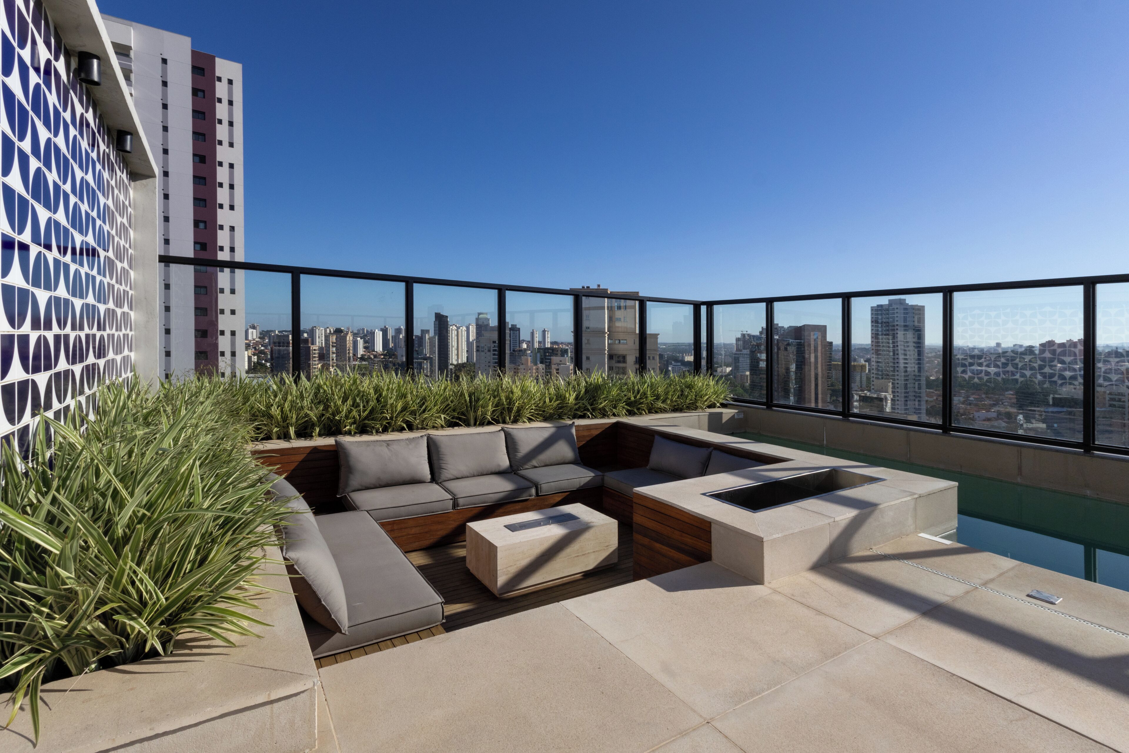 Une terrasse sur le toit dotée d’un espace salon extérieur moderne, d’une piscine et offrant une vue panoramique sur la ville.