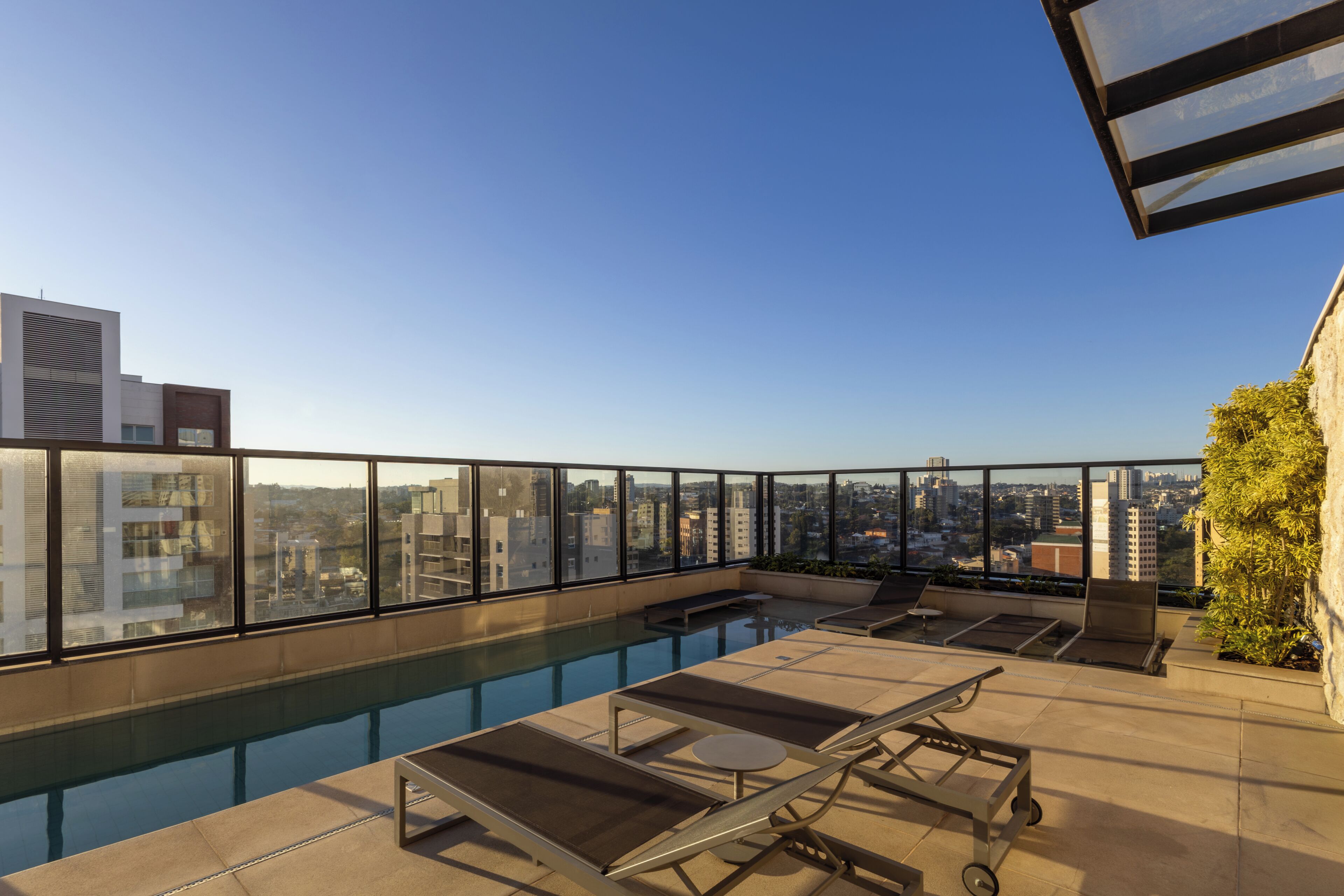 A rooftop pool area with lounge chairs and a view of the cityscape.