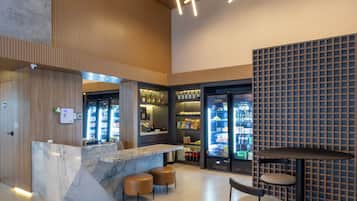 A modern bar area with a marble counter, stools, and a seating area with a table and chairs.