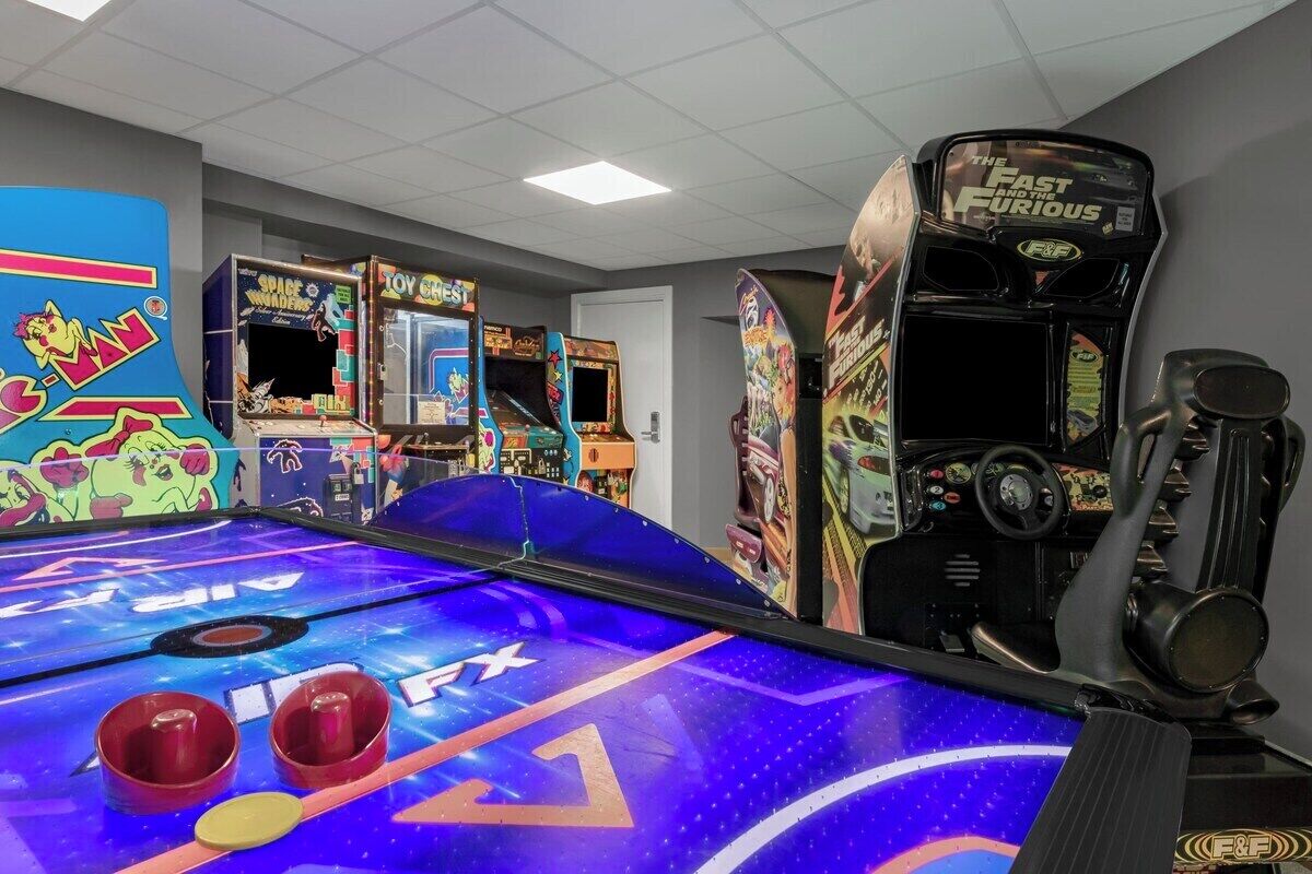 Une salle d’arcade proposant divers jeux, notamment un jeu de course et un jeu sur le thème de l’espace.