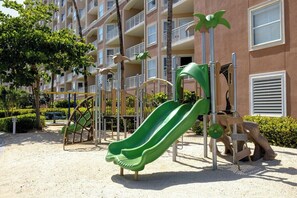 A playground with slides and climbing structures, surrounded by a building with balconies. - 1 Bedroom Villa at Marriott Aruba Surf Club (Noord)