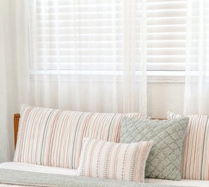 A room with a bed, a window with blinds, and a wall.