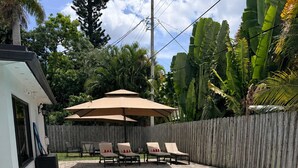A swimming pool with two inflatable rings, a wooden fence, and a covered patio area with chairs. - Spacious 5-bedroom Modern Retreat with Heated Pool Near Beach and Cove Shopping (Deerfield Beach)