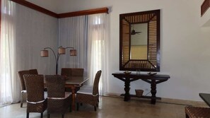 A dining area with a table and chairs, a mirror, and a lamp. - Caribbean bungallow with 2 bedrooms in Cap Cana (Punta Cana)