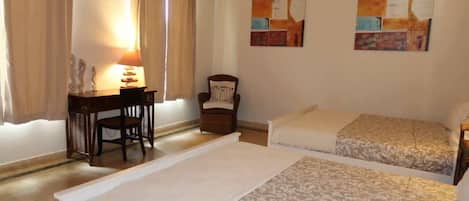 Een kamer met twee bedden, een bureau, een stoel en een lamp.