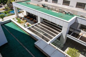 Um edifício moderno com piscina no terraço, área de estar externa e vários aparelhos de ar condicionado.