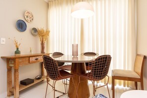A dining area with a round table, four chairs, a vase with dried flowers, and a lamp. - 1BR Apt, Full Condo, Jardim Goias - Mbca0407 (Goiânia)