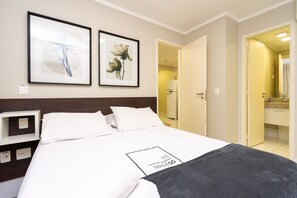 A hotel room with a bed, a nightstand, a framed picture, and a door leading to a bathroom. - 1BR Apt, Full Condo, Jardim Goias - Mbca0407 (Goiânia)