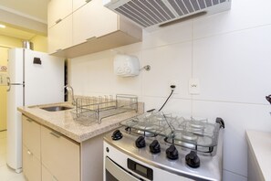 Uma cozinha com fogão a gás, pia e torradeira.