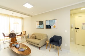Una sala moderna con sofá, sillón, mesa de centro y comedor con sillas y una mesa.