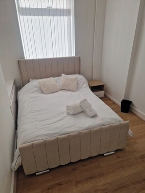 A neatly made bed with a headboard, a bedside table, and a small wooden nightstand. - 3BR House in Barrow-in-Furness | Near transpo | ST (Barrow-in-Furness)