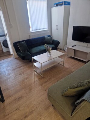 A living room with a sofa, a coffee table, a television, and a cabinet. - 3BR House in Barrow-in-Furness | Near transpo | ST (Barrow-in-Furness)