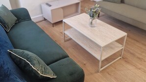 A living room with a green sofa, a coffee table, a TV, and a door in the background. - 3BR House in Barrow-in-Furness | Near transpo | ST (Barrow-in-Furness)