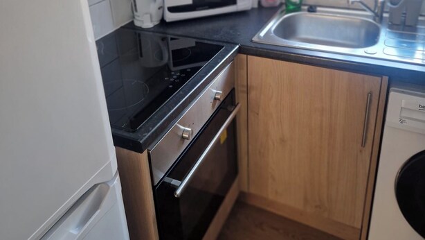 A compact kitchen with a stove, microwave, and sink. - 3BR House in Barrow-in-Furness | Near transpo | ST (Barrow-in-Furness)