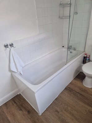 A bathroom with a white bathtub, a glass shower enclosure, and a toilet. - 3BR House in Barrow-in-Furness | Near transpo | ST (Barrow-in-Furness)