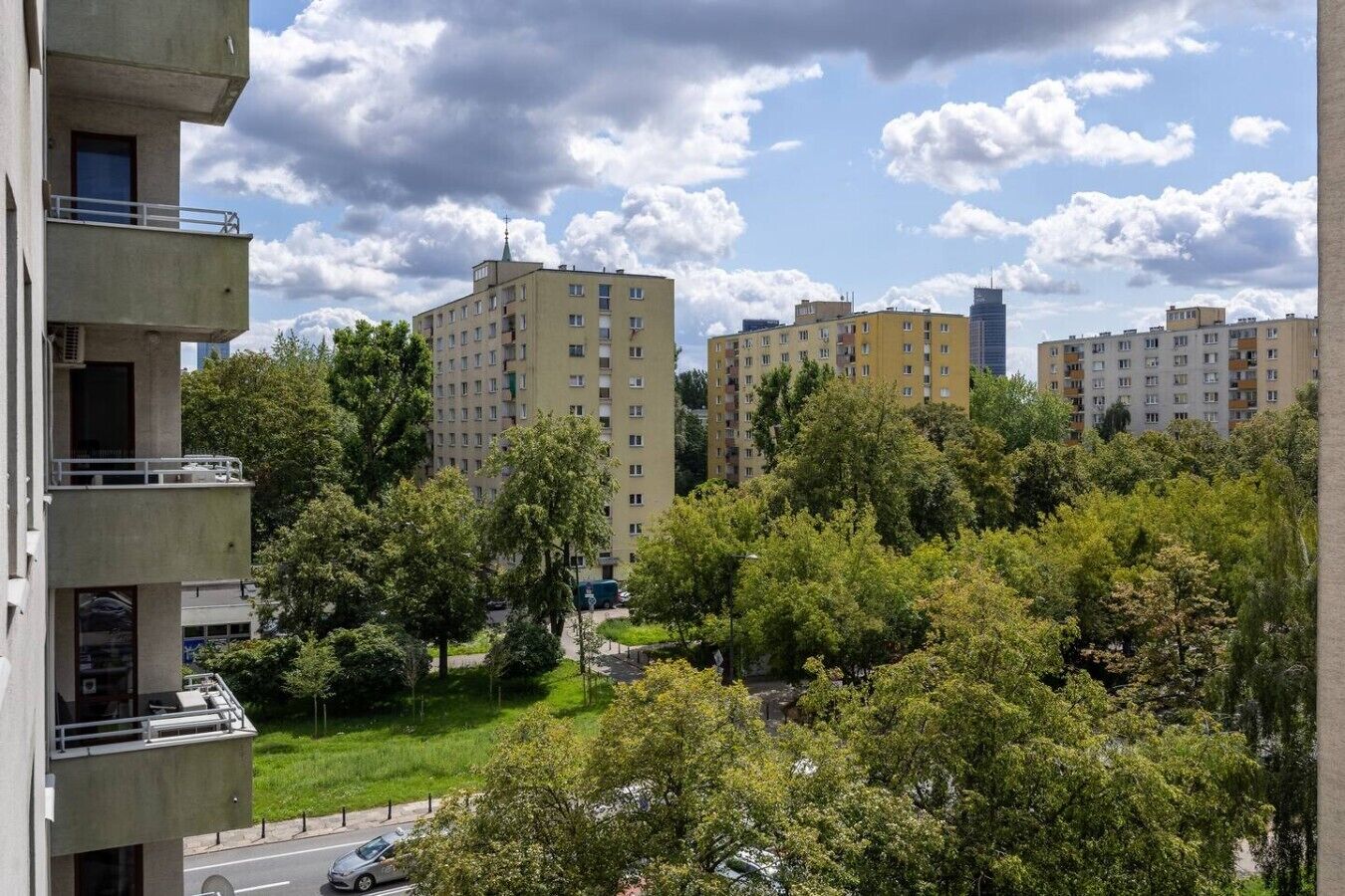 A residential area with multi-story apartment buildings, a street, and trees.