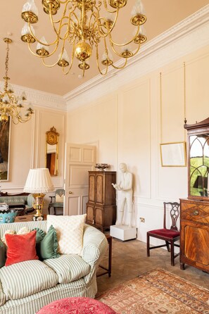 A room with a chandelier, a statue, a wooden cabinet, and a patterned rug. - Grand City Centre House (Edinburgh)