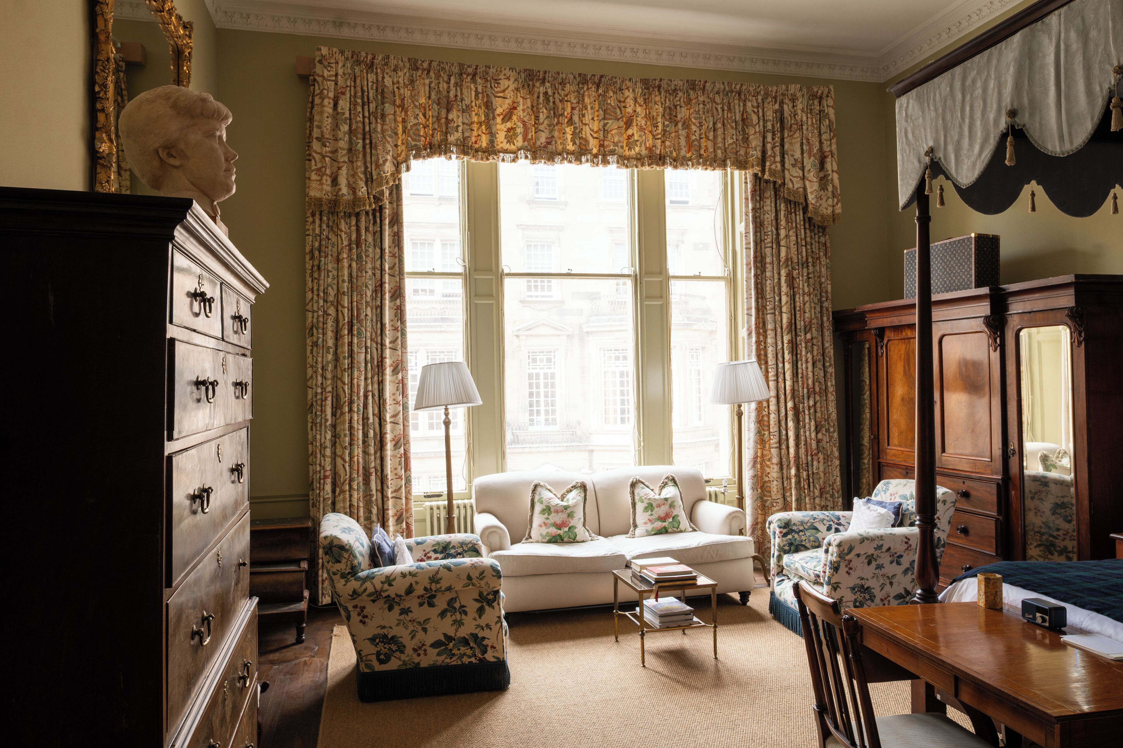 A room with a sofa, armchairs, a wooden cabinet, and a dining table.