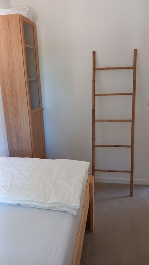 Ein Schlafzimmer mit einem hölzernen Bett, einem Holzschrank und einer Holzleiter an der Wand.