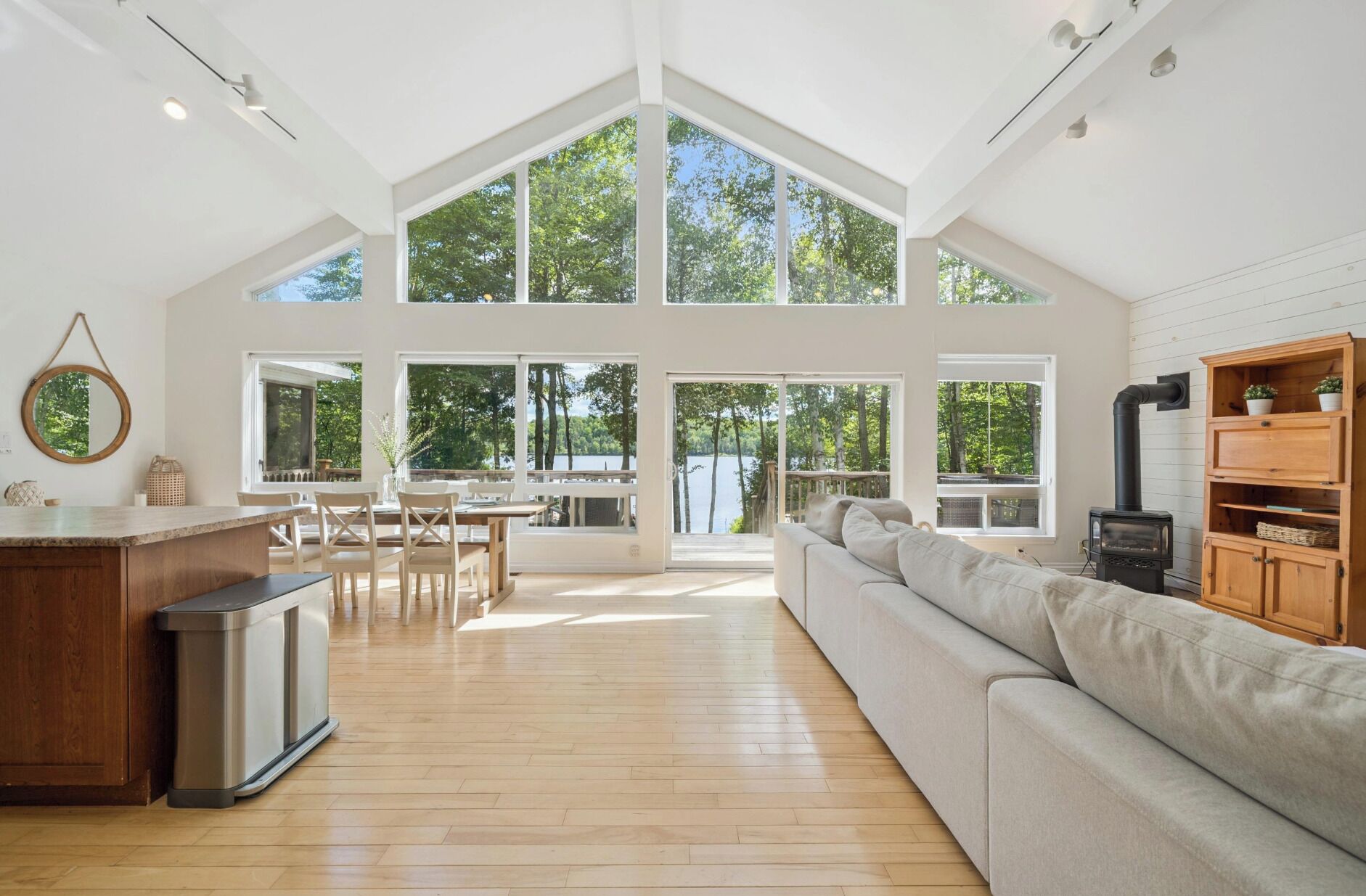 A spacious living area with a high ceiling, large windows, a central fireplace, and a cozy seating arrangement.