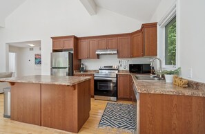 A modern kitchen with wooden cabinets, stainless steel appliances, and a granite countertop.