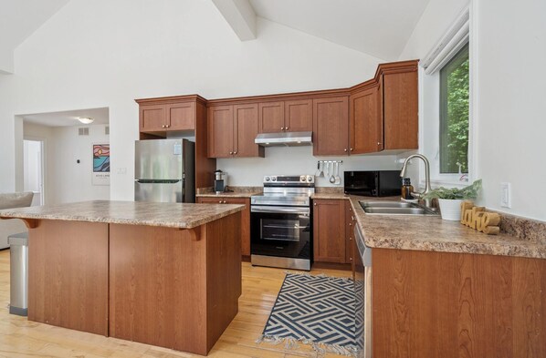 A modern kitchen with wooden cabinets, stainless steel appliances, and a granite countertop.