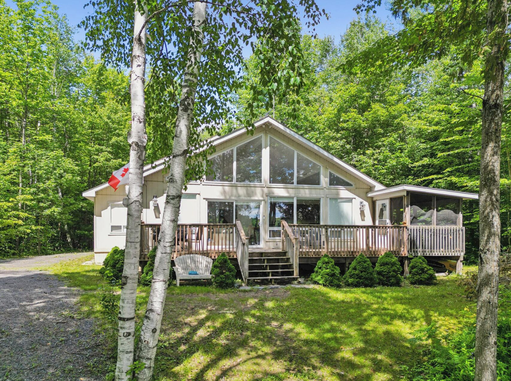 A two-story house with a deck, surrounded by trees.