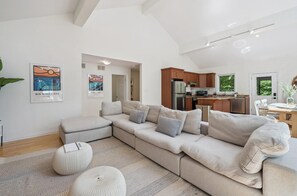 A modern living room with a sectional sofa, ottomans, and a herringbone-patterned rug.