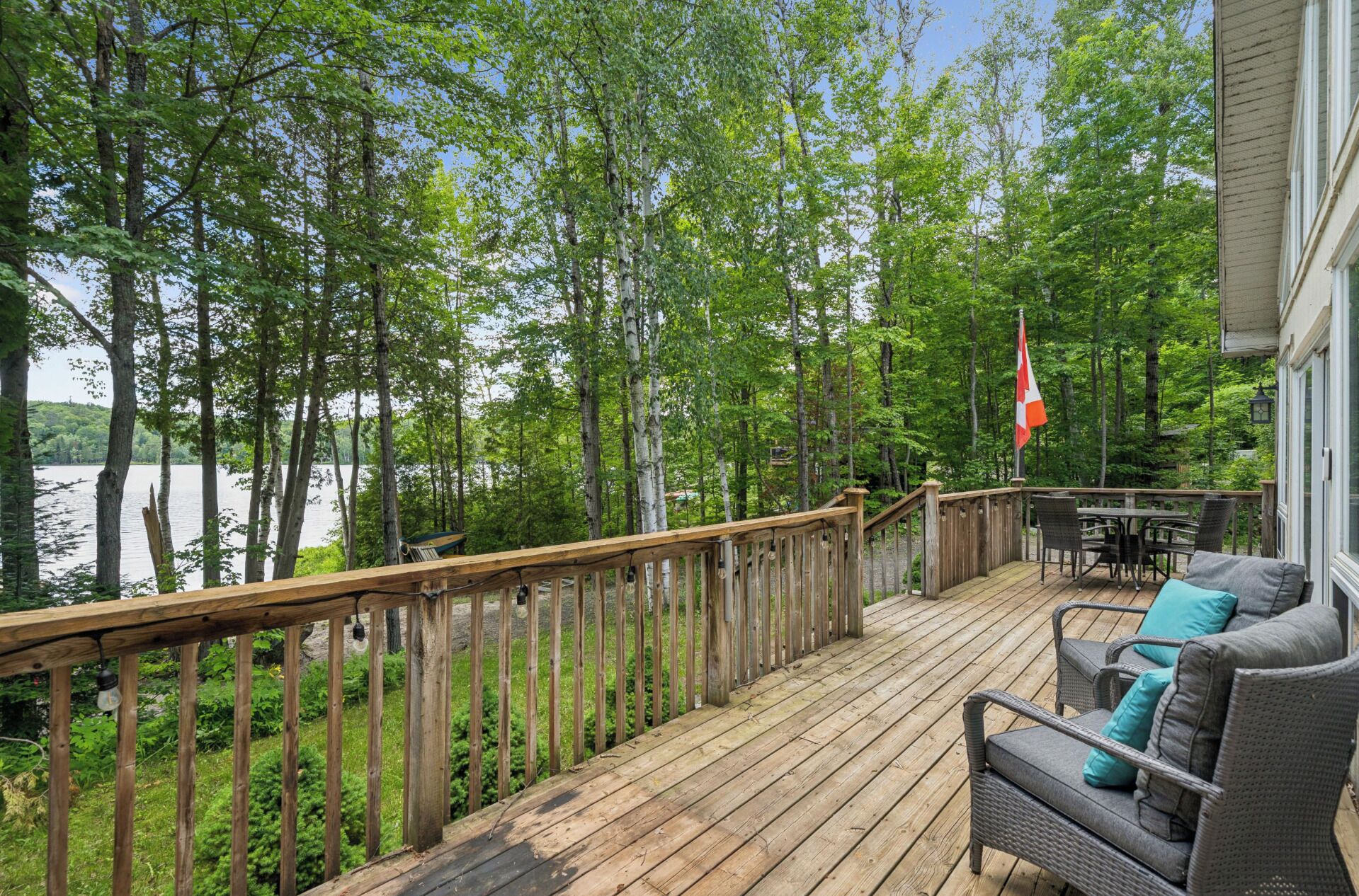 Une terrasse en bois dotée d’une balustrade, d’où l’on a vue sur un lac, le tout entouré d’arbres.