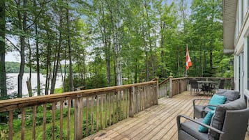 Une terrasse en bois dotée d’une balustrade, d’où l’on a vue sur un lac, le tout entouré d’arbres.