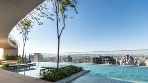 A rooftop pool with a city view, surrounded by greenery and modern architecture. - Ária Higienópolis by WeCare Hosting (São Paulo)