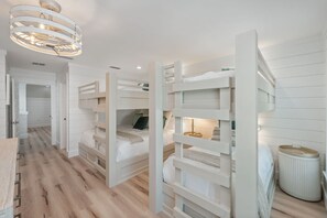 Een kinderkamer met stapelbedden, een houten vloer en een moderne lamp.