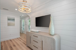 A hallway with a wooden floor, a white wall-mounted TV, a decorative vase, and a door with glass panels. - Seahorse: New 30A beach home! 1.6 miles to Seaside (Santa Rosa Beach)